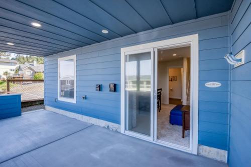 a blue house with a sliding glass door at The Captains Lookout Sleeps 6, Hot Tub, Pet Friendly, Ocean View in Depoe Bay