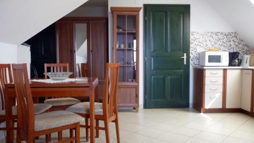 a kitchen with a table and chairs and a green door at Hillside Apartments in Révfülöp