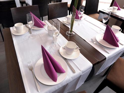 una mesa con servilletas moradas sobre un mantel blanco en Hotel Schweizer Hof en Kassel