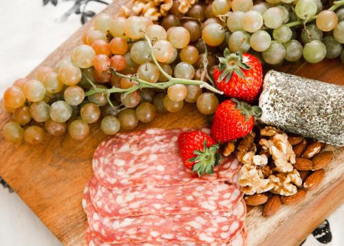 a cutting board with meat grapes strawberries and nuts at Naramata Courtyard Suites in Naramata