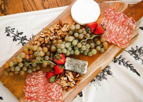 a cutting board with meat and fruit on a table at Naramata Courtyard Suites in Naramata