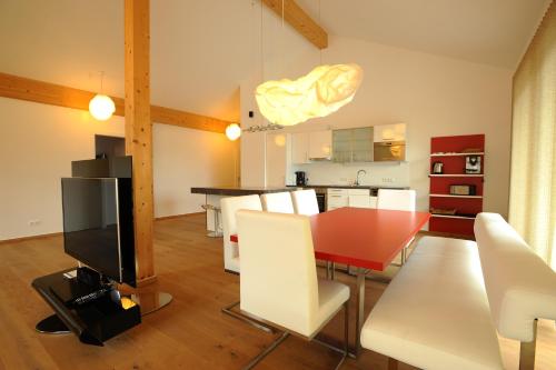 comedor y cocina con mesa roja y sillas blancas en Penthouse Alpine Living direkt an der Skipiste by Schladmingurlaub, en Haus im Ennstal