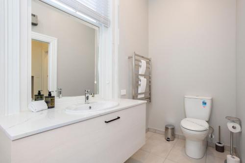 a white bathroom with a toilet and a sink at Character on Stuart St in Dunedin