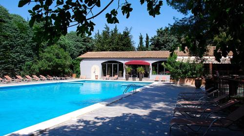 una grande piscina con sedie e un edificio di Hotel Les Mazets Des Roches a Tarascona