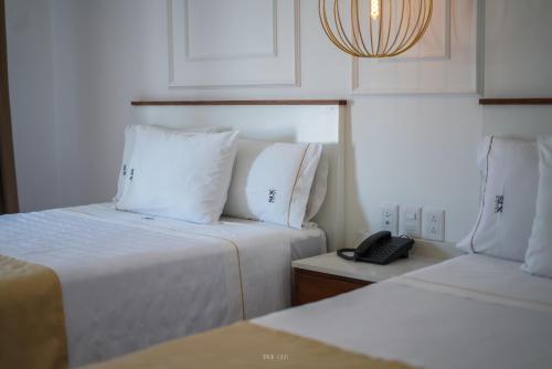 a room with two beds and a phone on a table at Six Hotel Guadalajara Degollado in Guadalajara
