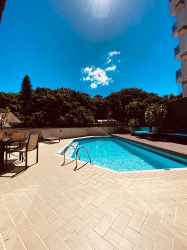una piscina con una mesa y una silla junto a ella en Apart-hotel, piscina, TV a cabo, academia, en Joinville