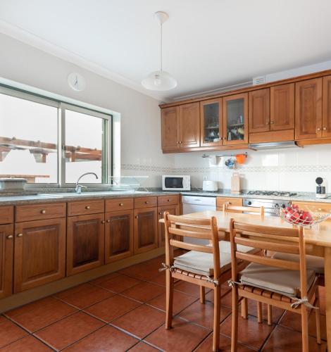 a kitchen with wooden cabinets and a table and chairs at Gelfa Beach House in Viana do Castelo