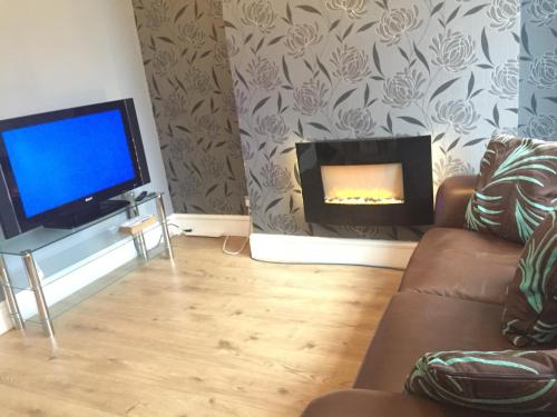 a living room with a fireplace and a tv at Private double room near City centre, Coventry in Coventry