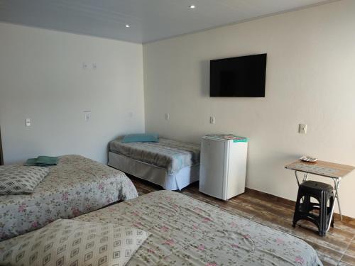 a room with three beds and a television on the wall at Suítes e PENHA-SC in Penha