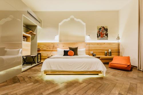 Schlafzimmer mit einem Bett mit orangefarbenem Kissen in der Unterkunft Tá Hotel de diseño in Querétaro