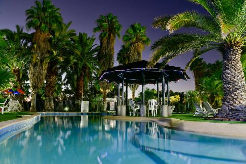 a swimming pool with a gazebo and palm trees at Desert Palms Alice Springs in Alice Springs