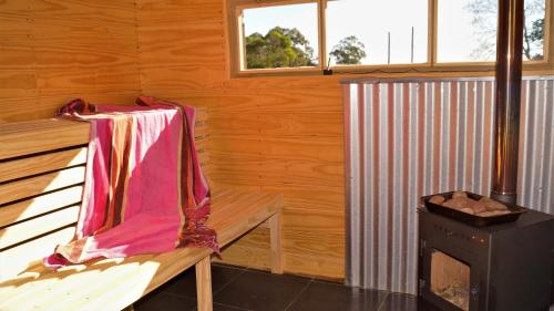 Cabaña de madera con banco y fogones en La Chacra Holandesa, en Atlántida