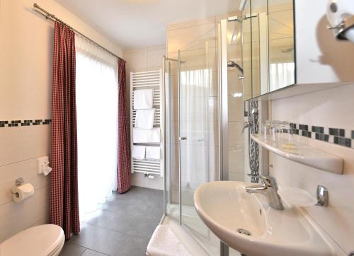y baño con lavabo y ducha. en Hotel AlpIn Bed & Breakfast, en Fischen