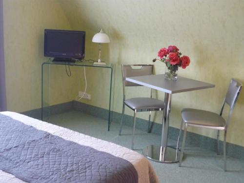 - une chambre avec un lit et une table ornée d'un vase de fleurs dans l'établissement Le Miramont, à Orincles