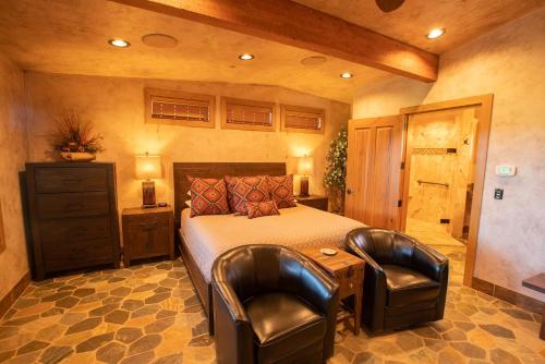 a bedroom with a bed and two leather chairs at Cougar Ridge Resort in Torrey