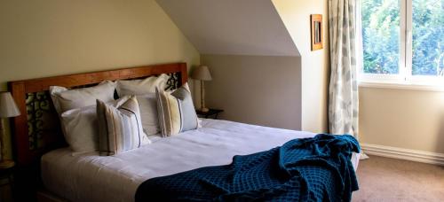 a bedroom with a bed with white sheets and pillows at Queenstown Country Lodge in Queenstown