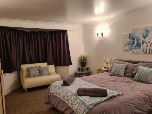 a bedroom with a large bed and a chair at Westbury House in Rochford