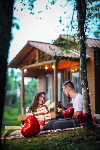 a man and woman sitting on a blanket in front of a house at La Nostra Terra in Nova Veneza