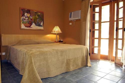 a bedroom with a bed and a lamp and a window at Ilha Flat Hotel Ap 2202 in Ilhabela