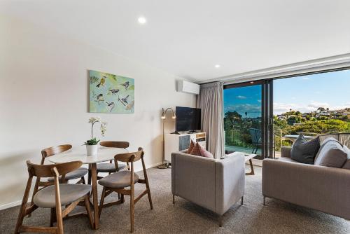 a living room with a table and chairs and a couch at FERNZ Motel & Apartments Birkenhead in Auckland