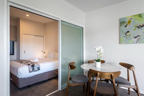 a bedroom with a bed and a table and chairs at FERNZ Motel & Apartments Birkenhead in Auckland