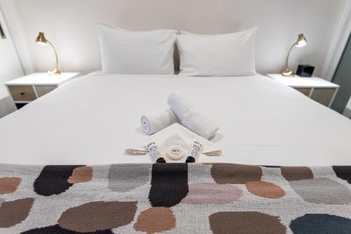 a bedroom with a bed with two towels and two lamps at FERNZ Motel & Apartments Birkenhead in Auckland