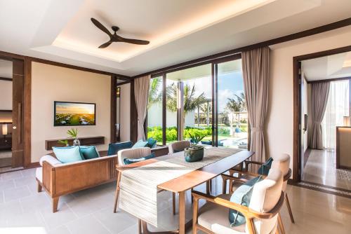 a dining room with a table and chairs and a couch at Maia Resort Quy Nhon in Quy Nhon