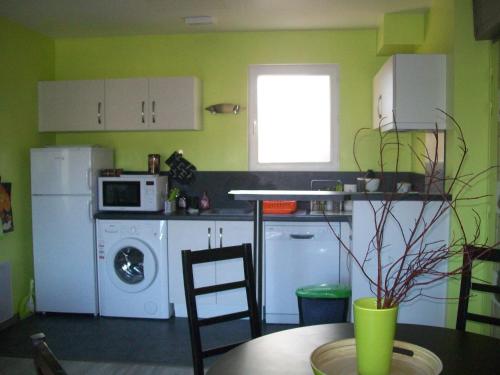 une cuisine avec des appareils blancs et une table avec une table dans l'établissement Au Jardin d'Eau, à Missillac