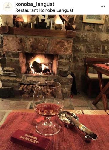 a glass of wine sitting on a table with a fireplace at Apartments PROVA in Sveti Stefan