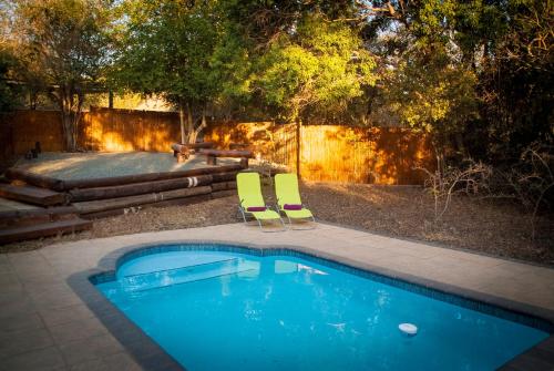 una piscina con 2 sillas, una mesa y una mesa de picnic en Umkhumbi Lodge, en Hluhluwe