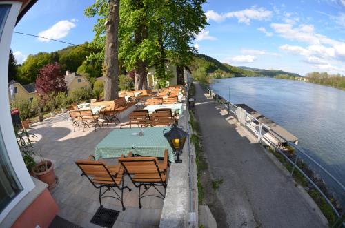 a row of tables and chairs next to a river at Fischwirtshaus Landmotel Die Donaurast in Persenbeug-Gottsdorf