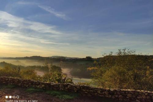 a view of a foggy field with a stone wall at La Belle Petite Ferme Rosiers de Julliac 19350 in Les Bos