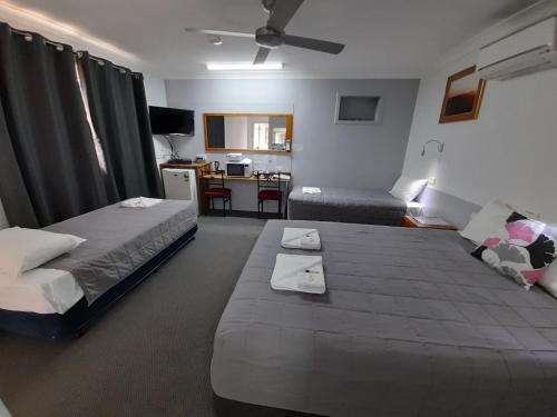 a hotel room with two beds and a desk at Civic Motel Grafton in Grafton