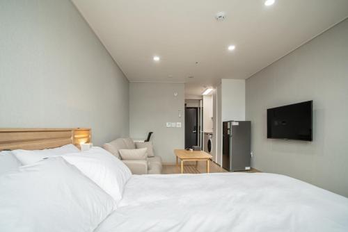 a bedroom with a white bed and a television at Jeju Central Park Residence in Jeju