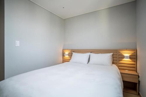 a bedroom with a white bed with two lamps at Jeju Central Park Residence in Jeju