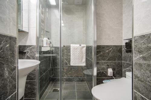 a bathroom with a shower and a sink and a toilet at Jeju Central Park Residence in Jeju