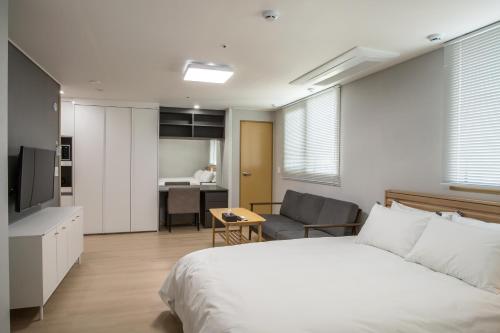 a bedroom with a bed and a living room at Jeju Central Park Residence in Jeju