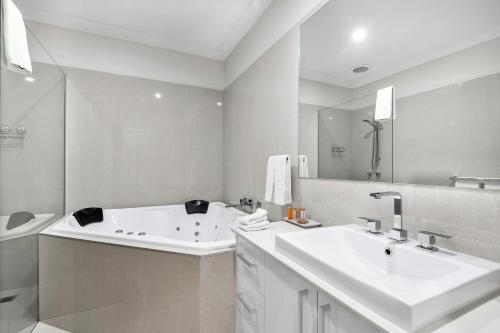 a white bathroom with two sinks and a tub at The Oxley Estate in Portarlington