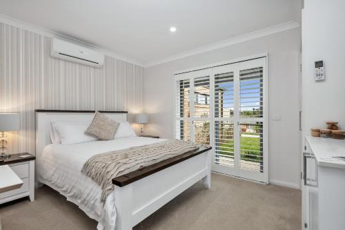 a white bedroom with a bed and a window at The Oxley Estate in Portarlington