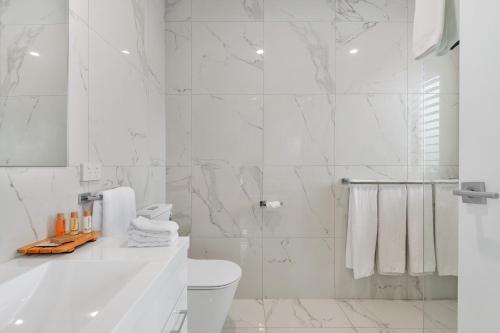 a white bathroom with a tub and a toilet at The Oxley Estate in Portarlington