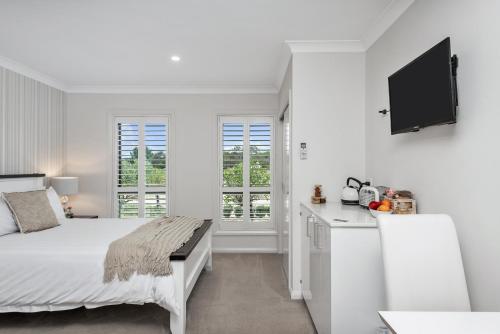 a white bedroom with a bed and a kitchen at The Oxley Estate in Portarlington
