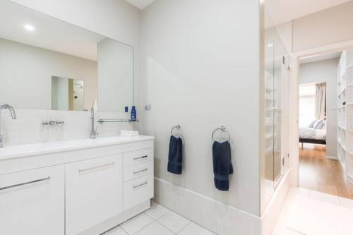 uma casa de banho branca com um lavatório e um chuveiro em Luxe at Brooklyn - Hawkesbury River Marina em Brooklyn