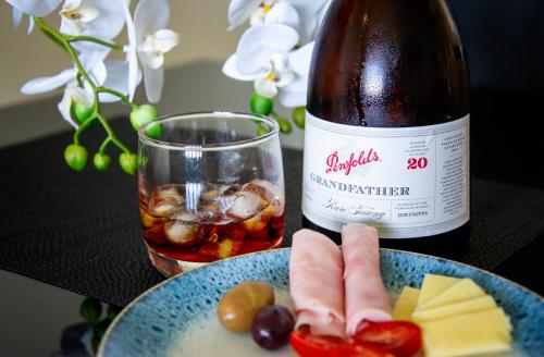 a bottle of wine sitting next to a plate of food at Absolute Waterfront - Tropical Sunrise Apartment Over The Water in Darwin