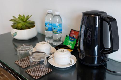 a black coffee maker on a counter with glasses and water bottles at Azura Gold Hotel & Apartment in Nha Trang