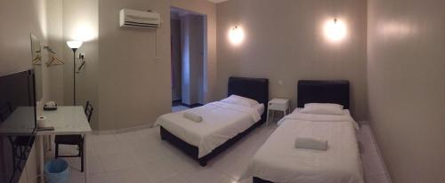 a bedroom with two beds and a desk and a mirror at Homestay Muar in Muar
