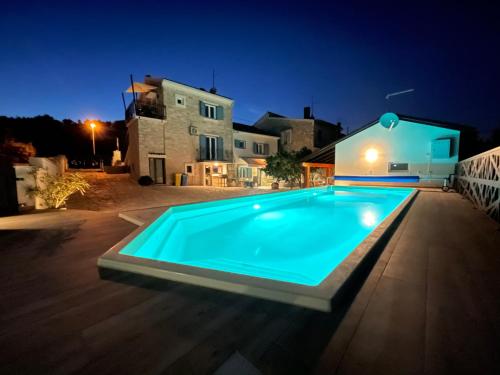 a swimming pool at night with a house in the background at Apartments Nona in Pula