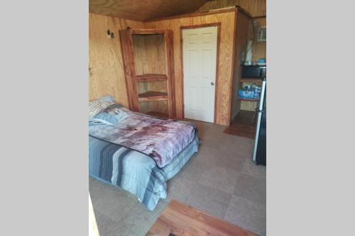 um pequeno quarto com uma cama e uma cozinha em Tiny Cabin at the DonkeyRanch em Medicine Park