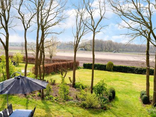 an umbrella in a garden with trees and a field at Vacation home with Jacuzzi in Schoonloo
