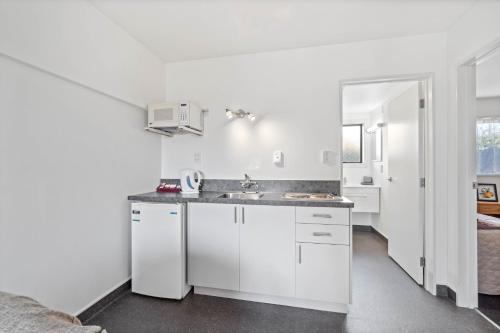 a kitchen with white cabinets and a sink at Ascot Vale Motor Lodge in Christchurch