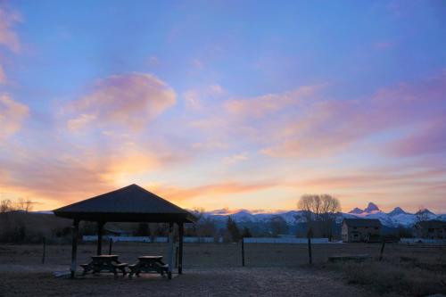 a picnic shelter with two benches and a sunset at Teton Peaks Resort in Tetonia